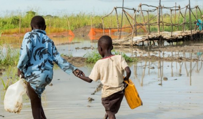Bentiu, South Sudan, two boys walk in a river