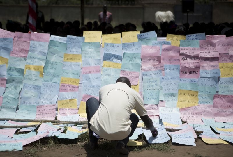 Uganda,  Kitgum. Families of missing persons stick placards with the names of their missing loved ones onto a display board during the International day of the Disappeared. 