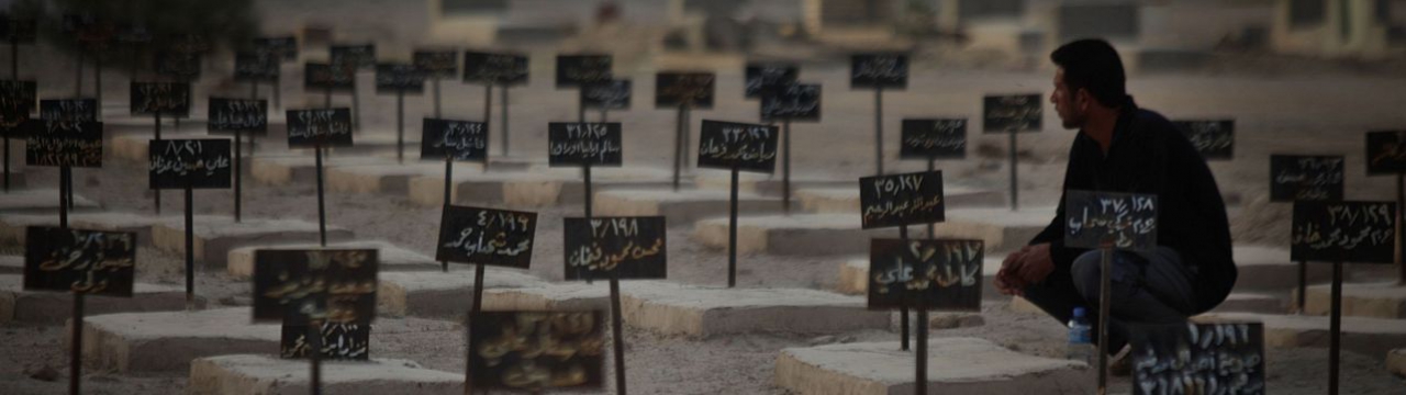Man sitting in front of a graveyard (tombstones in arabic)