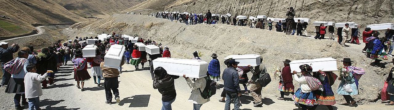 Group of people carrying coffins down the mountain