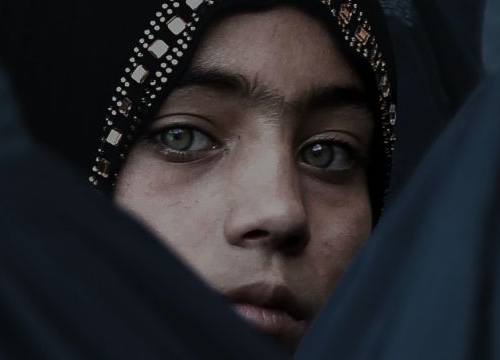 A Girl Looks on Among Afghan Women Lining Up To Receive Relief Assistance, During The Holy Month of Ramadan in Jalalabad, Afghanistan.