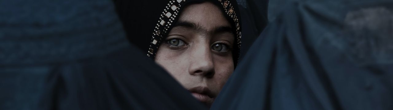 A Girl Looks on Among Afghan Women Lining Up To Receive Relief Assistance, During The Holy Month of Ramadan in Jalalabad, Afghanistan.