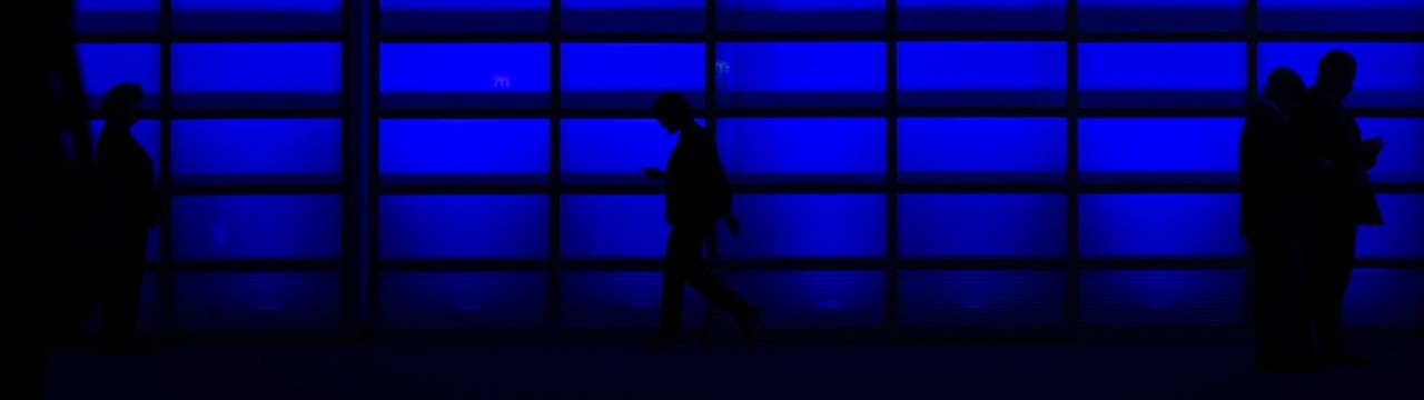 Persons walking in front of a blue wall