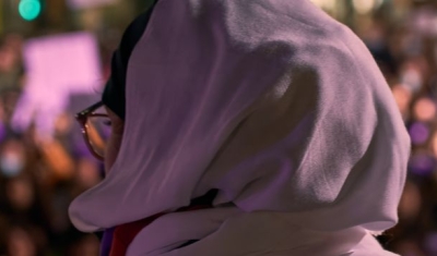 Portrait of an arab woman from the back facing a crowd at a feminist demonstration