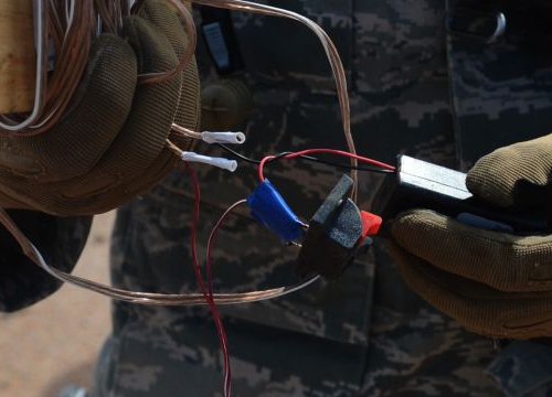 A soldier examines components of an improvised explosive device.
