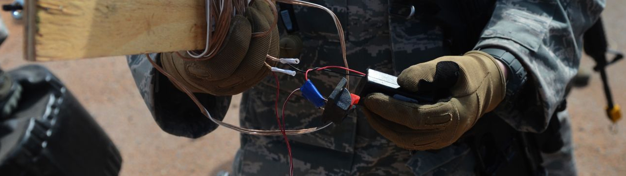 A soldier examines components of an improvised explosive device.