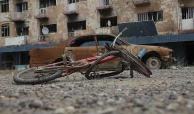 Ukraine, damaged bicycle and car in front of a destroyed building