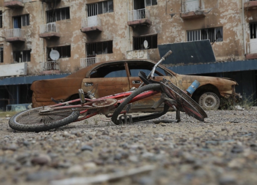 Ukraine, damaged bicycle and car in front of a destroyed building