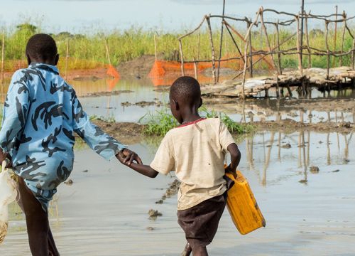 Bentiu, South Sudan, two boys walk in a river