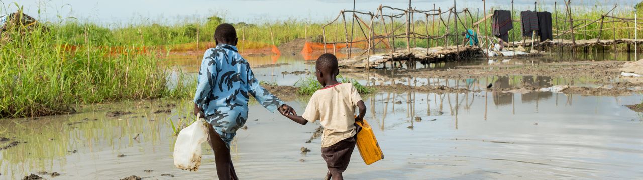 Bentiu, South Sudan, two boys walk in a river