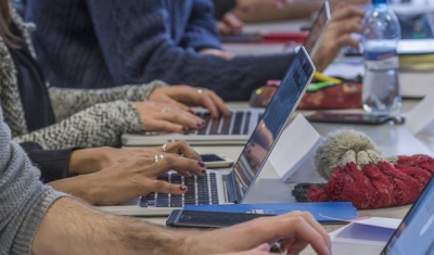 Persons at a desk and typing on their computer