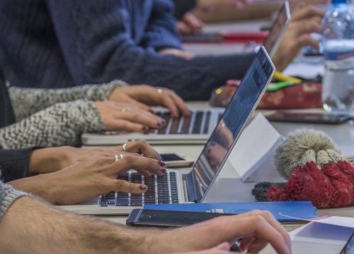 Persons at a desk and typing on their computer