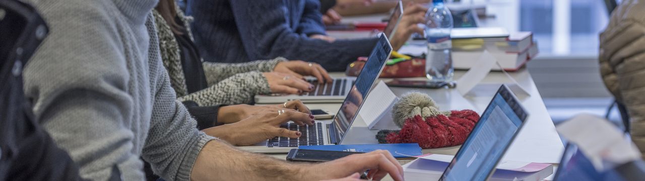 Persons at a desk and typing on their computer