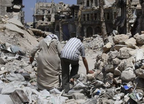 Two persons walk in the ruins of Aleppo