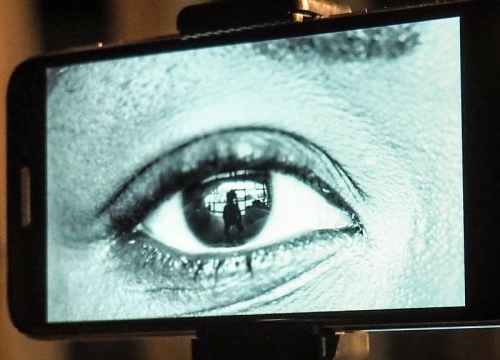 Photo of an art installation: The installation is made up of robots with eyes. When a user begins to interact with their smartphone, one of the robot eyes opens and begins looking around the room. When the interaction is over, the eye closes again.