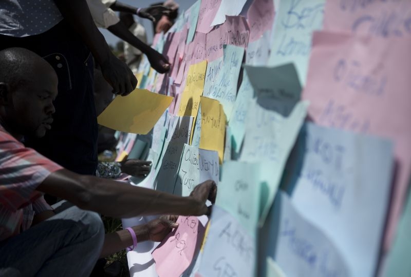 Uganda, Kitgum. Families of missing persons stick placards with the names of their missing loved ones onto a display board during the International day of the Disappeared. 