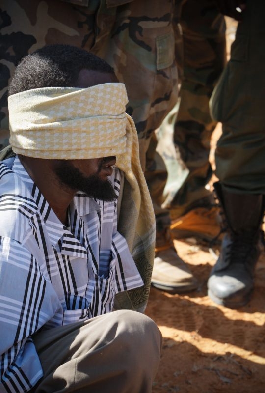 An alleged suspect of the Al-Qaeda-affiliated extremist group Al Shabaab are guarded at a former police station by soldiers of the Somali National Army (SNA)