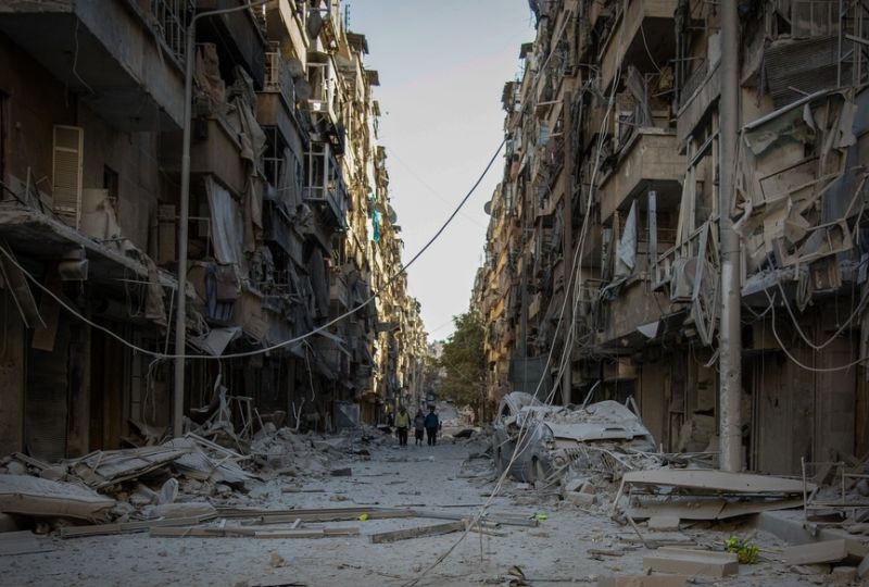 East Aleppo, Syria: People walk down a street in Bustan Al Kasr neighbourhood after it was hit by airstrikes in mid-October 2016. 