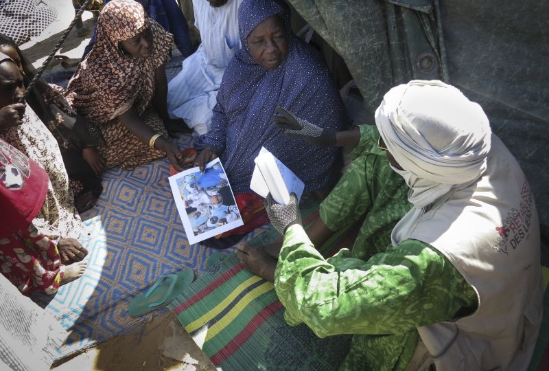 Niger,  Refugee site of Gamari. A restoring family links' volunteer from the Red Cross Society of Niger is showing to the family mother the first photos of her three daughters reunited in Diffa. 