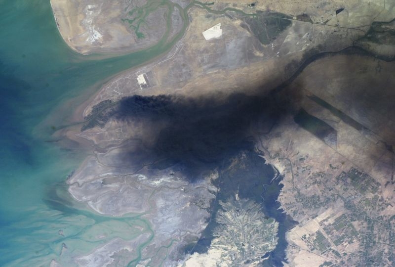 large black smoke plume over southeastern Iraq was taken by an Expedition 8 crewmember on the International Space Station. The oil that is burning spilled from a ruptured pipeline on March 23, 2004.