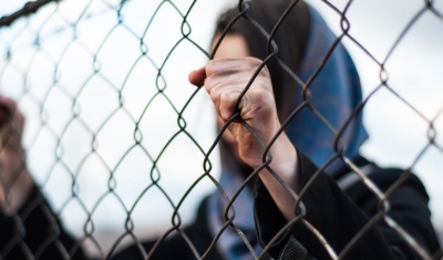A Migrant migrant is holding her hands behind the protective fence.