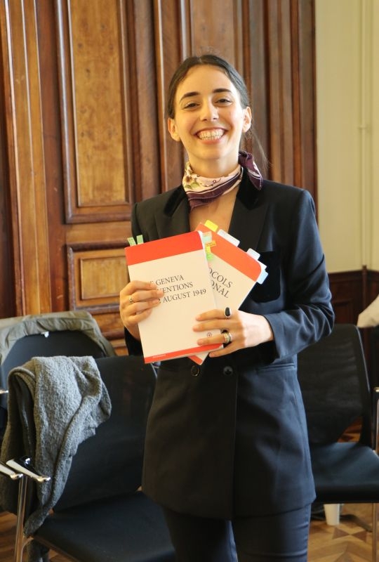 A student at the pleadings holding the Geneva Conventions and their additional protocols